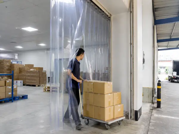 Xe đẩy đi qua rèm nhựa PVC trong suốt tại kho hàng